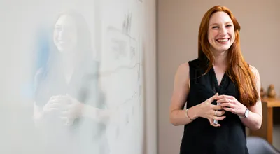 Picture of a happy smiling teacher standing in from of a whiteboard